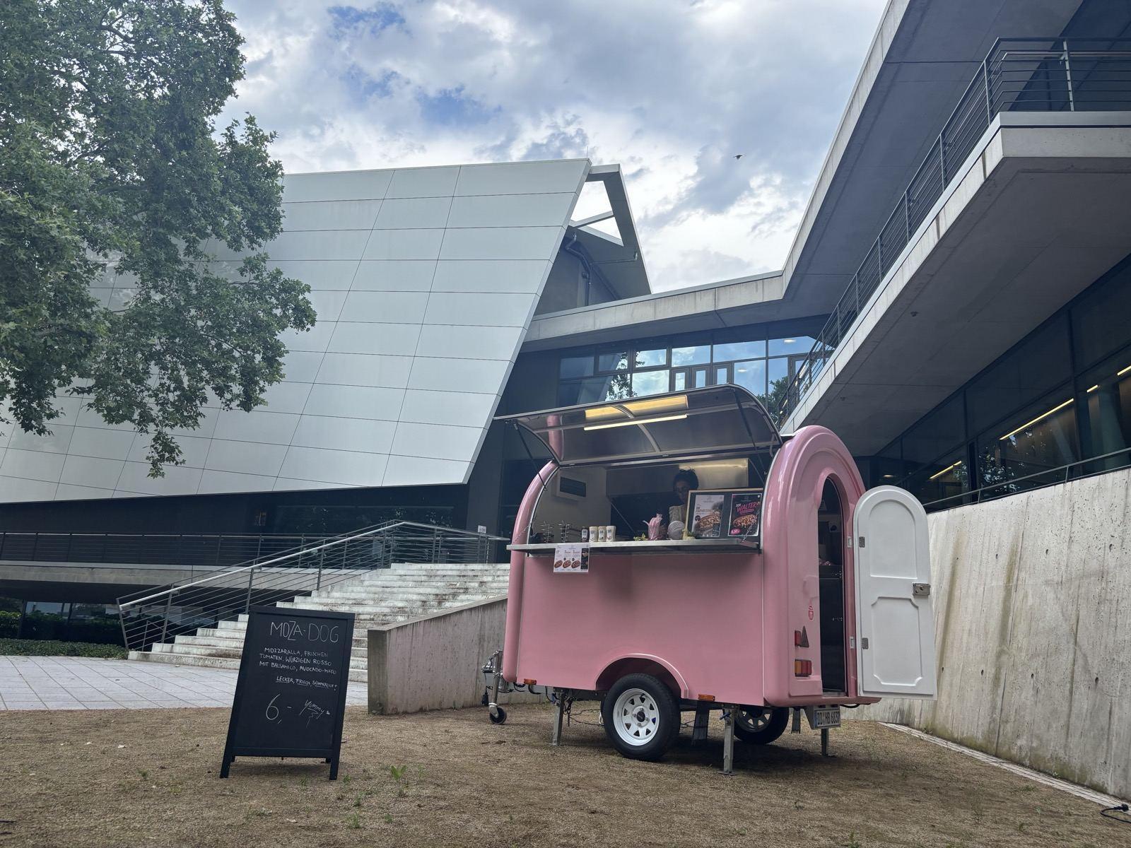 Der Foodtruck 21 EINUNDZWANZIG tagsüber im Einsatz vor einem modernen Gebäude